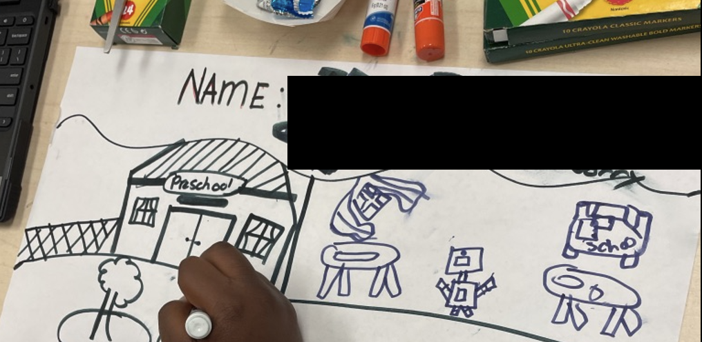 A hand drawing a robot story on a paper